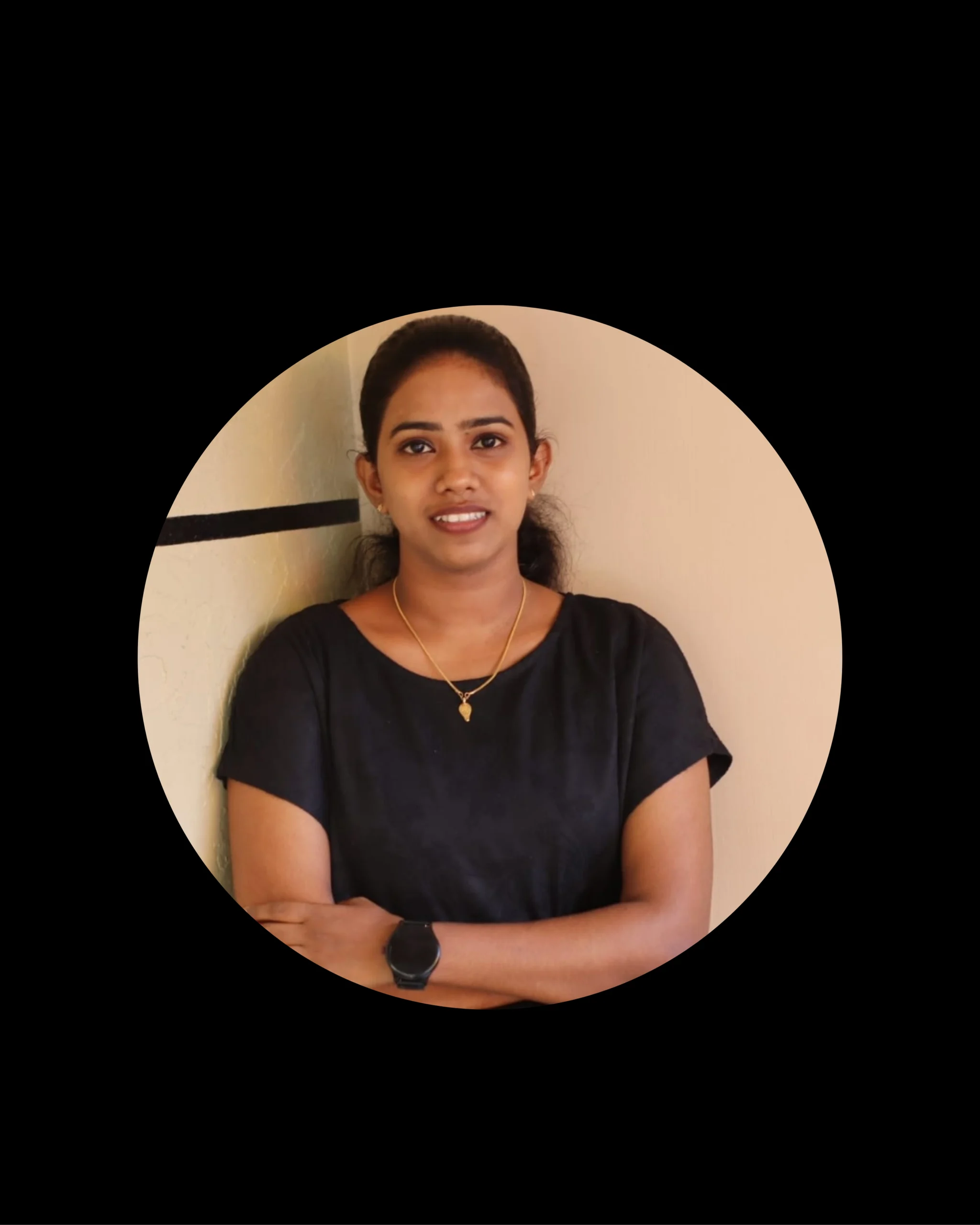 Portrait of a confident digital consultant in Kochi, standing with arms crossed and wearing a black outfit, smiling slightly against a beige wall background.